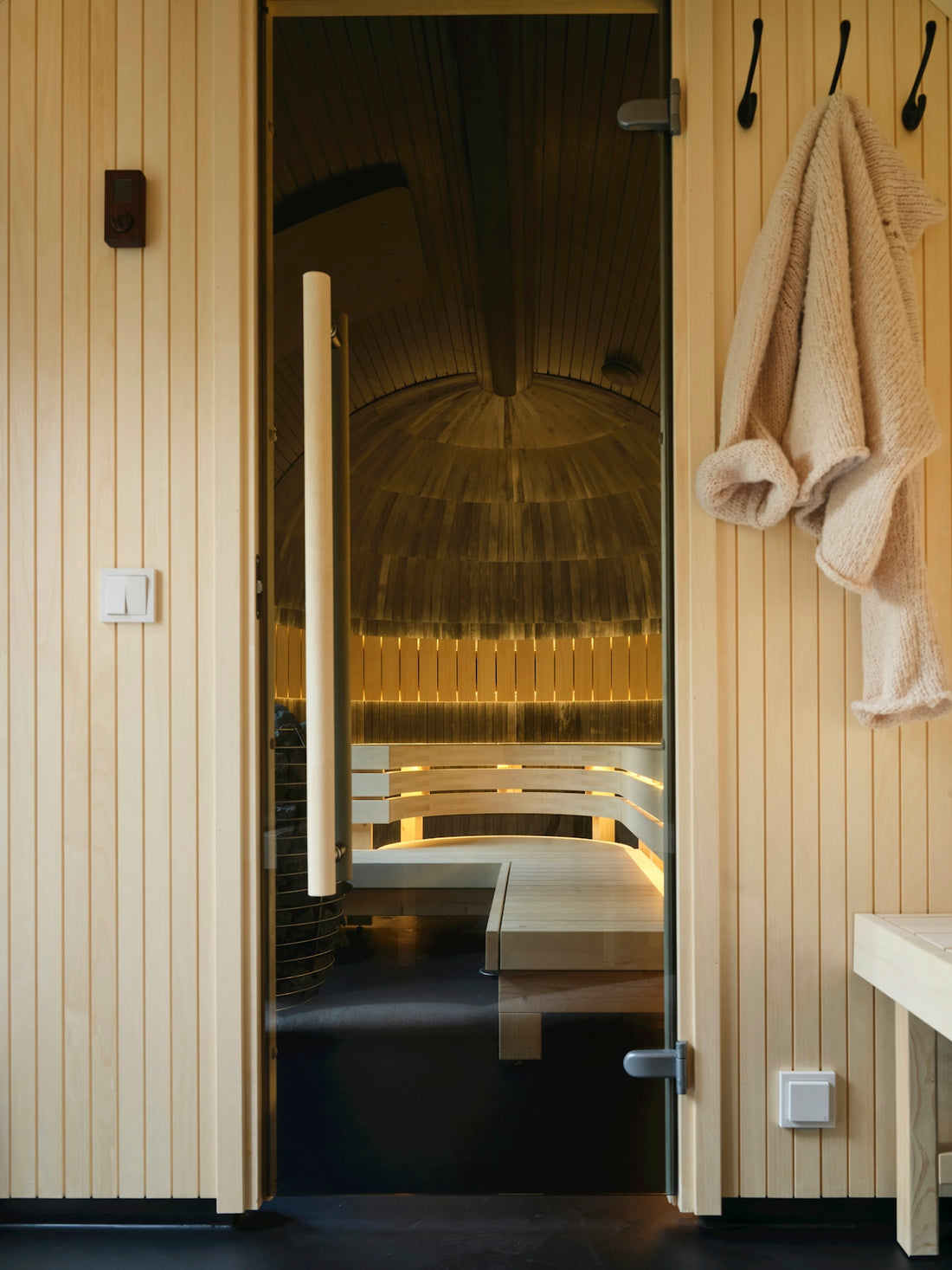 A bathroom with a bench and towels hanging on the wall