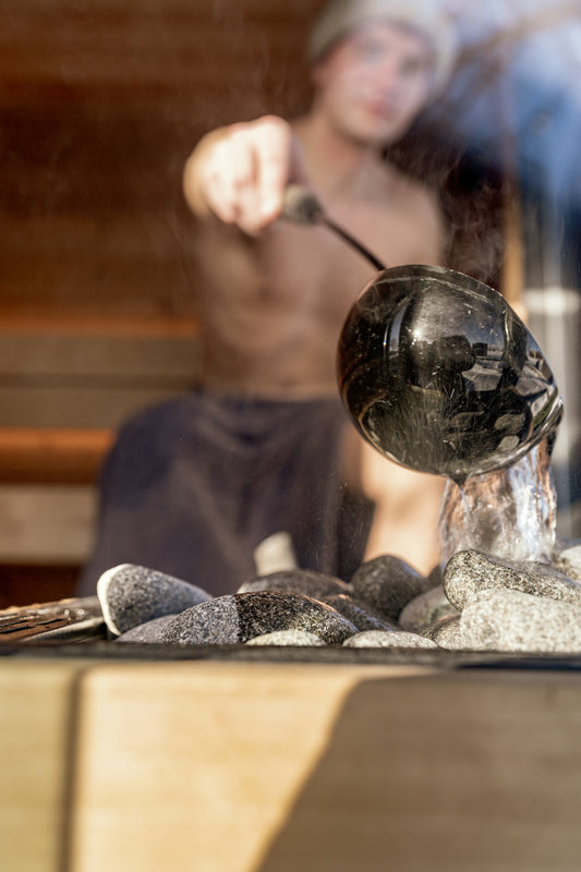 A man pours water onto hot sauna stones.