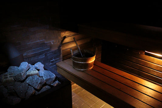 A sauna with rocks, a bucket, and wood.
