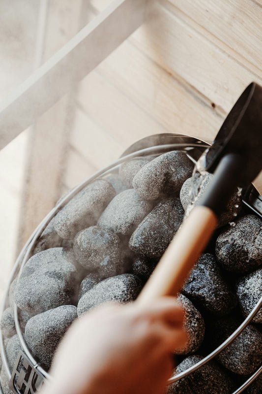 Someone is sprinkling water on sauna rocks.