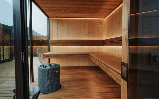 Modern wooden sauna with ambient lighting and stone heater.
